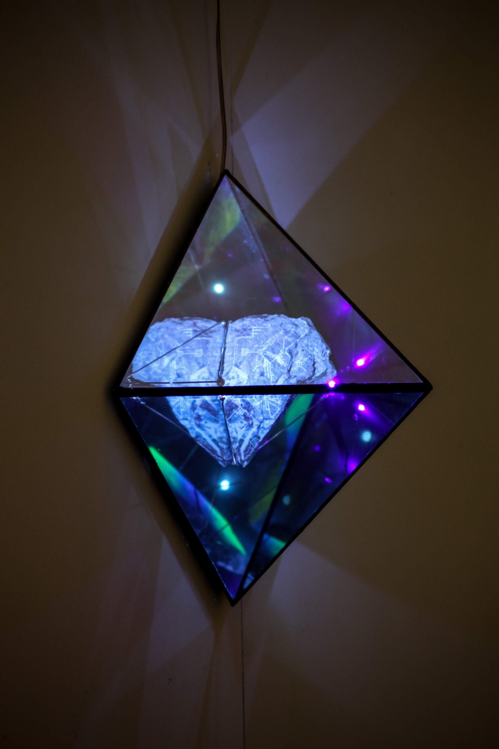 Engraved/UV painted rock, glass and mirror attached to wall with lights refracting from sculpture